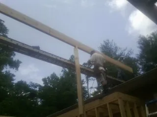 Carpenter setting a ridge beam over a new addition frame — Ice Dam Removal by Roofing Brothers in Columbus Junction