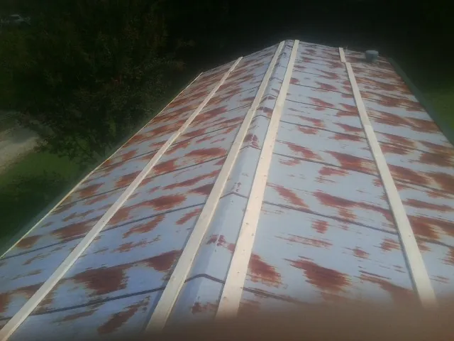 Rusted metal roof panels with new wood purlins before replacement — Storm Damage Roof Repair in Columbus Junction by Roofing Brothers