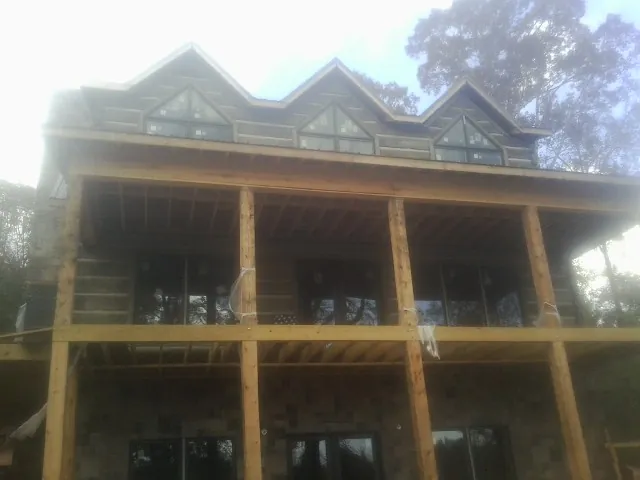 Dormers and porch framing on a large log home under construction — Roof Coating work by our crew in Columbus Junction