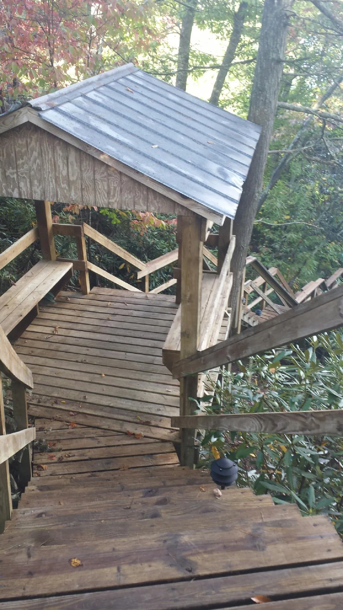 Metal roofed shelter over wooden steps on a wooded walkway — Skylight Repair & Installation work by our crew in Columbus Junction