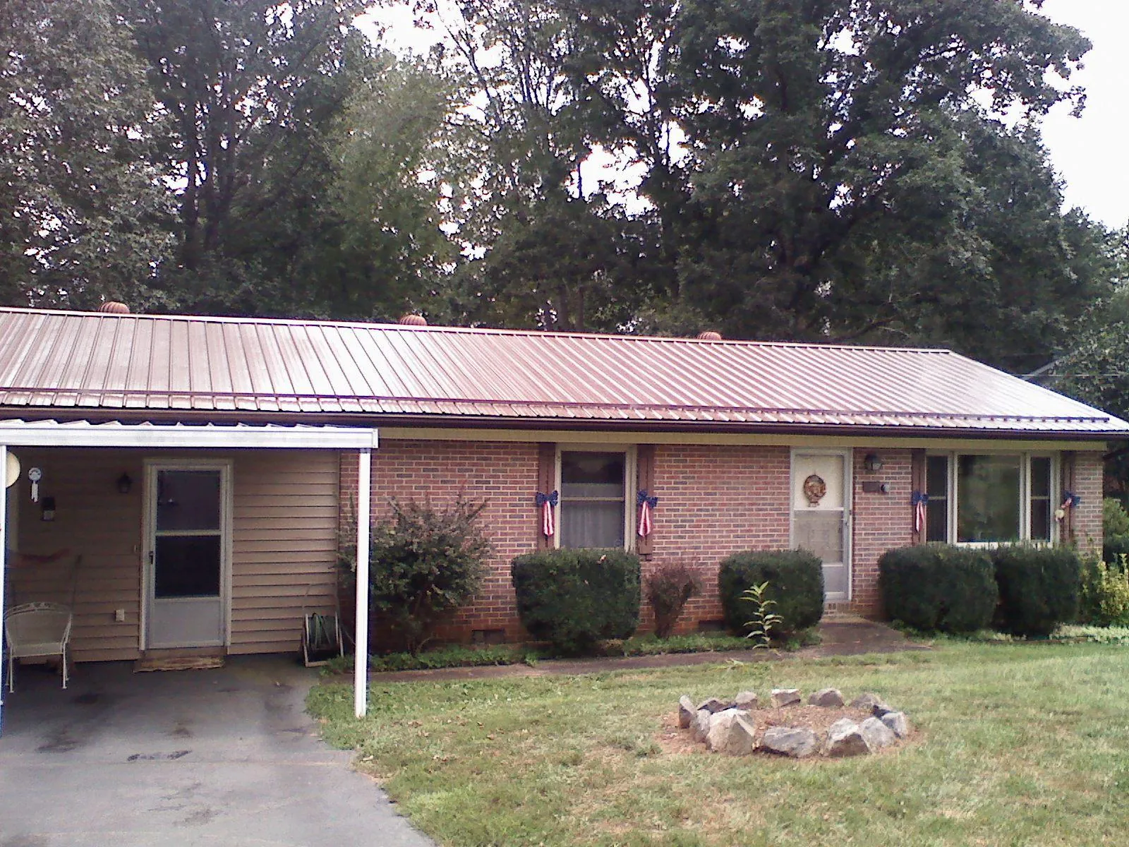 Bronze metal roof and carport on a brick ranch home — Roof Repair work by our crew in Columbus Junction